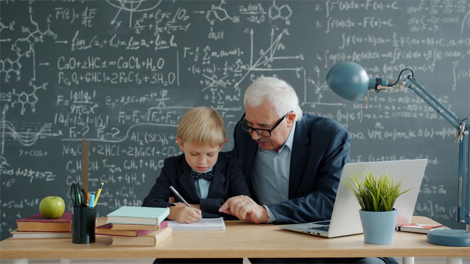A mature male tutor supporting a pupil with written work